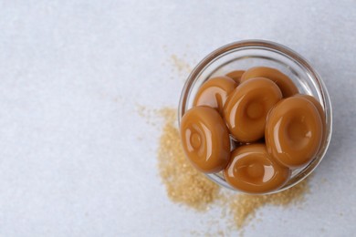 Photo of Tasty sweet caramel candies on white table, top view. Space for text