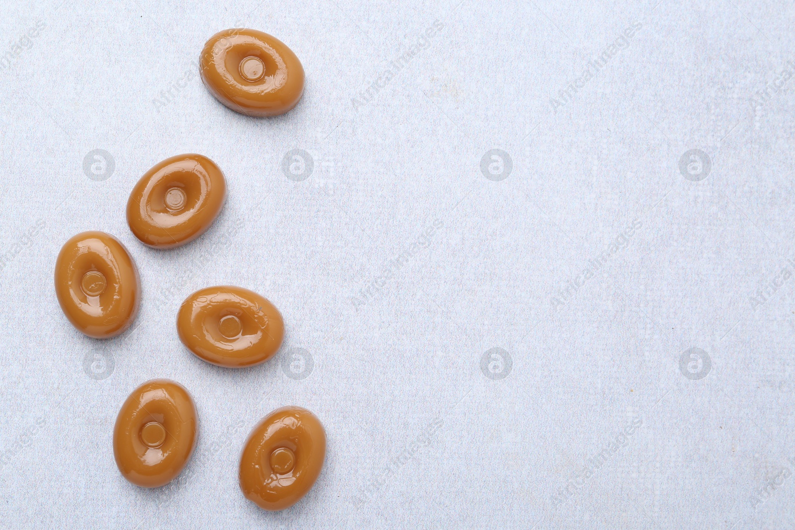 Tasty sweet caramel candies on white table, flat lay. Space for text Photo of Tasty sweet caramel candies on white table, flat lay. Space for text