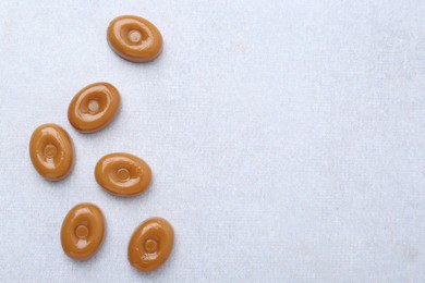 Photo of Tasty sweet caramel candies on white table, flat lay. Space for text