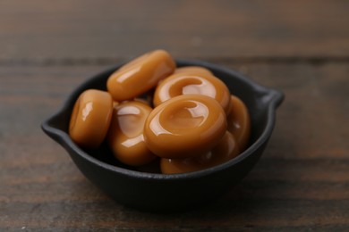Photo of Tasty sweet caramel candies on wooden table, closeup