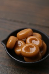 Photo of Tasty sweet caramel candies on wooden table, closeup