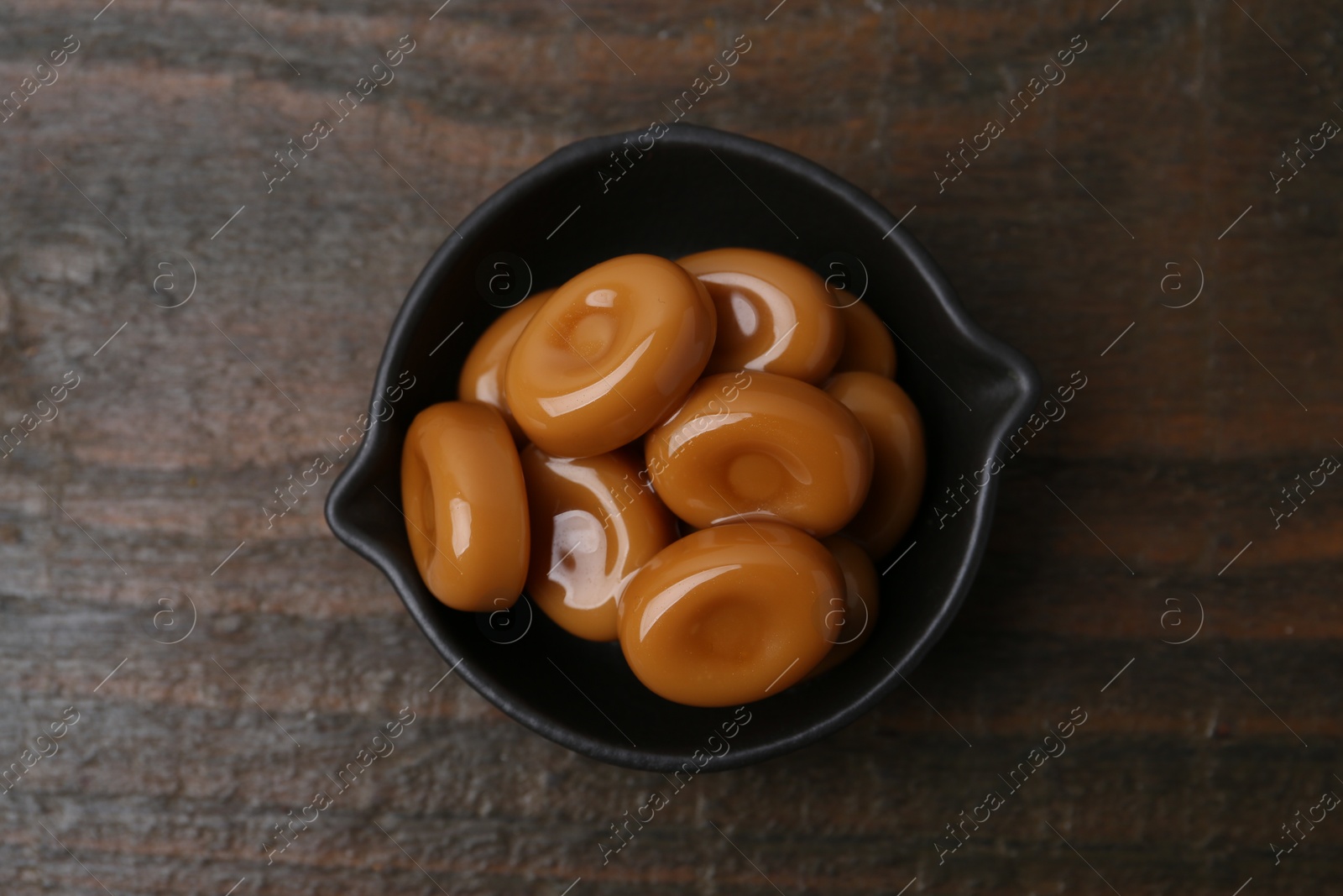 Tasty sweet caramel candies on wooden table, top view Photo of Tasty sweet caramel candies on wooden table, top view