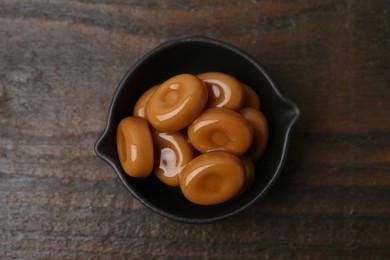 Photo of Tasty sweet caramel candies on wooden table, top view