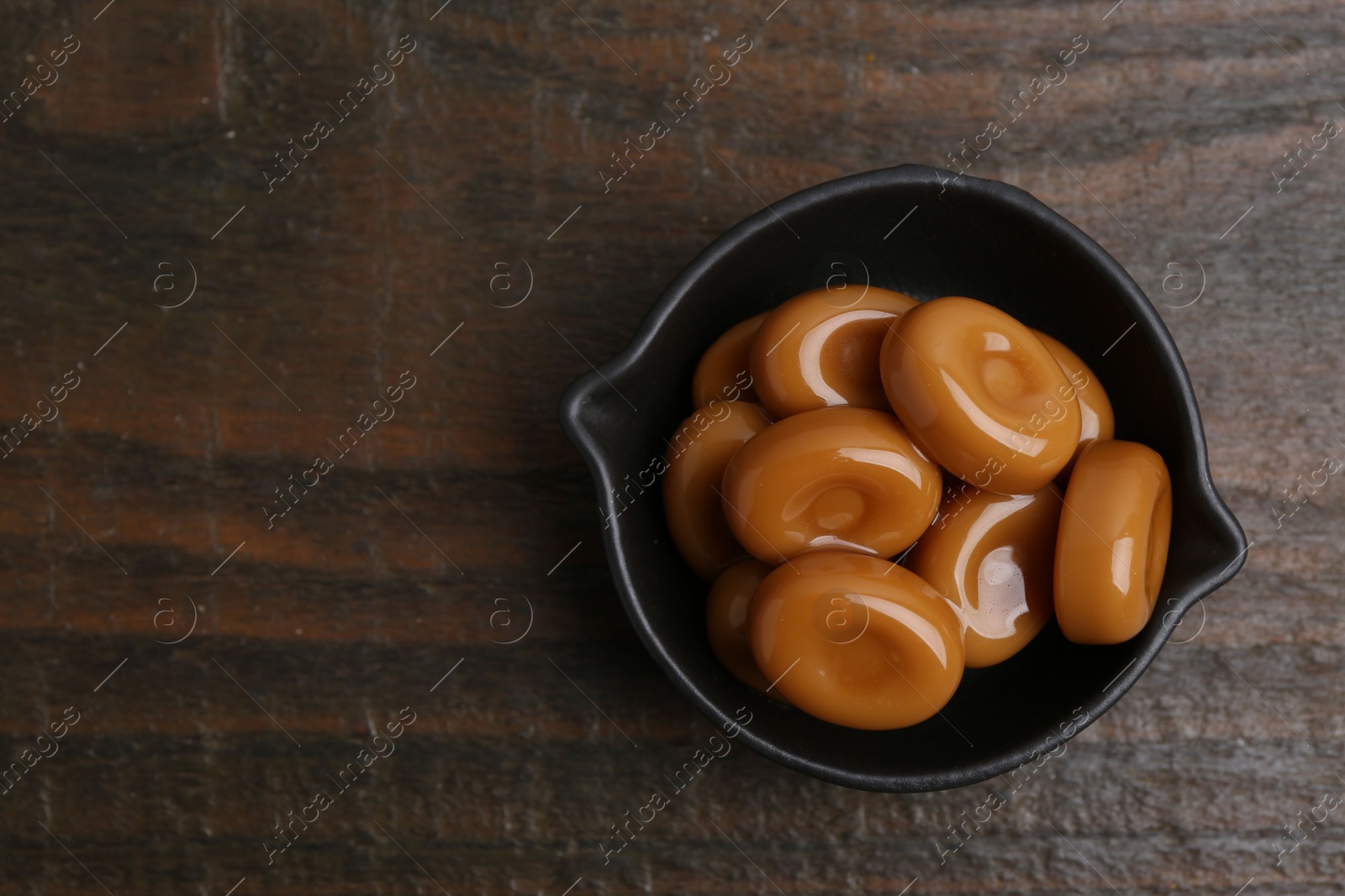 Tasty sweet caramel candies on wooden table, top view. Space for text Photo of Tasty sweet caramel candies on wooden table, top view. Space for text