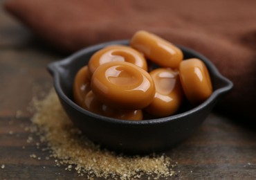 Photo of Tasty sweet caramel candies on wooden table, closeup