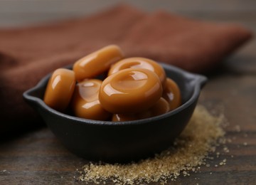 Photo of Tasty sweet caramel candies on wooden table, closeup