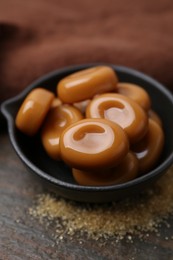 Photo of Tasty sweet caramel candies on wooden table, closeup