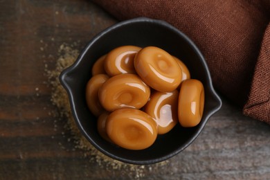 Photo of Tasty sweet caramel candies on wooden table, top view