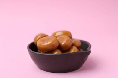 Photo of Tasty sweet caramel candies on pink background, closeup