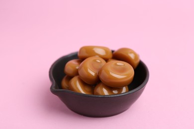 Photo of Tasty sweet caramel candies on pink background, closeup