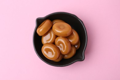 Photo of Tasty sweet caramel candies on pink background, top view