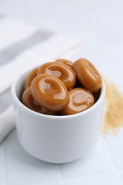 Photo of Tasty sweet caramel candies on white tiled table, closeup