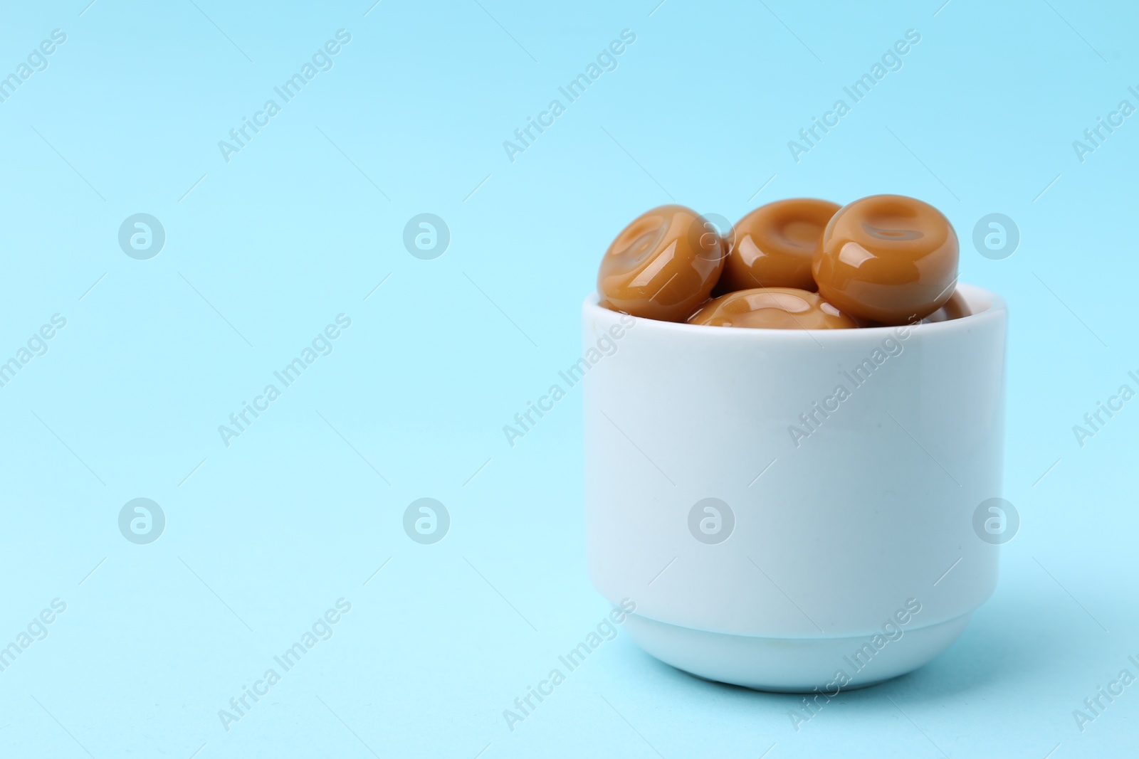 Tasty sweet caramel candies on light blue background, closeup. Space for text Photo of Tasty sweet caramel candies on light blue background, closeup. Space for text