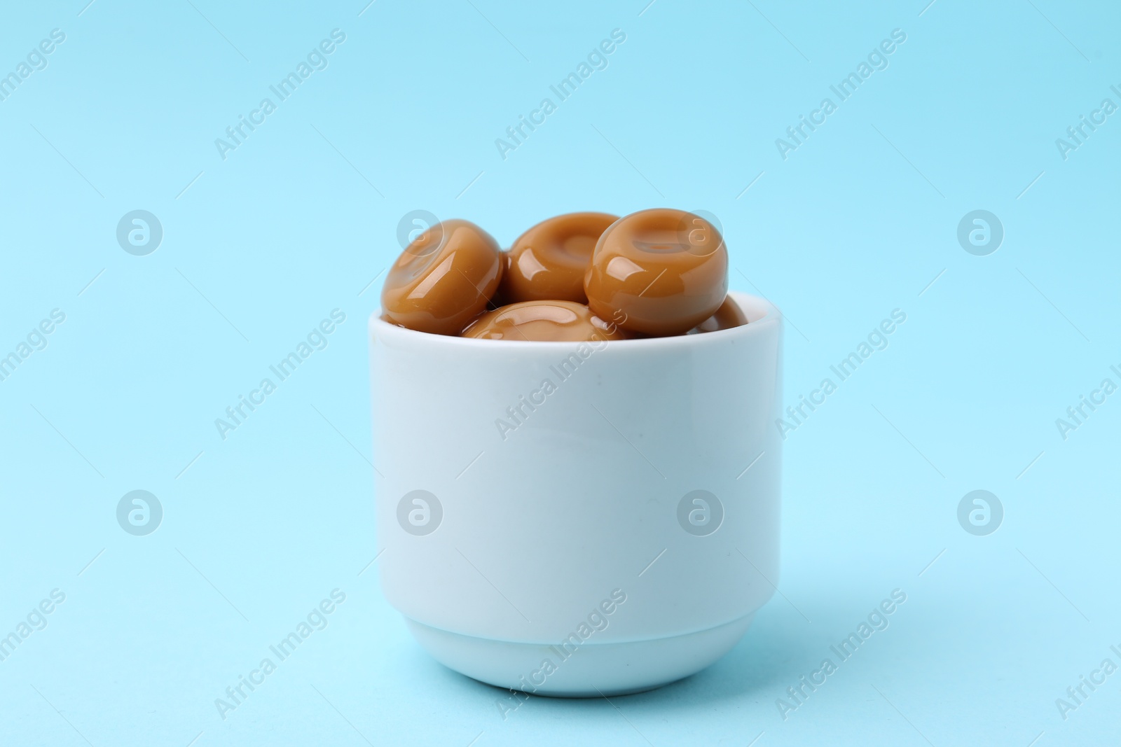 Tasty sweet caramel candies on light blue background, closeup Photo of Tasty sweet caramel candies on light blue background, closeup