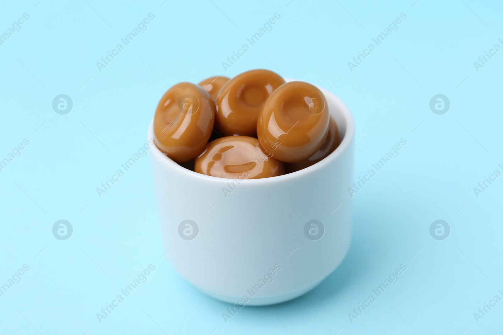 Tasty sweet caramel candies on light blue background, closeup Photo of Tasty sweet caramel candies on light blue background, closeup