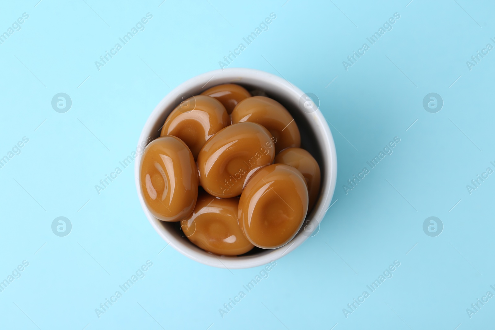 Tasty sweet caramel candies on light blue background, top view Photo of Tasty sweet caramel candies on light blue background, top view