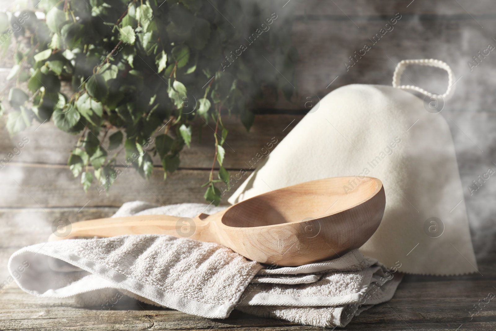 Sauna equipment. Felt wool hat, ladle and towel on wooden surface in steam Image of Sauna equipment. Felt wool hat, ladle and towel on wooden surface in steam