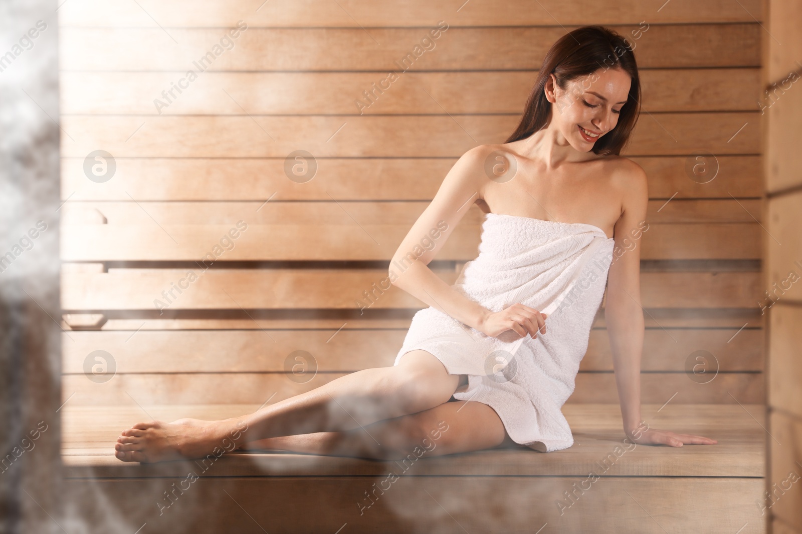 Beautiful woman relaxing on wooden bench surrounded by steam in sauna Image of Beautiful woman relaxing on wooden bench surrounded by steam in sauna