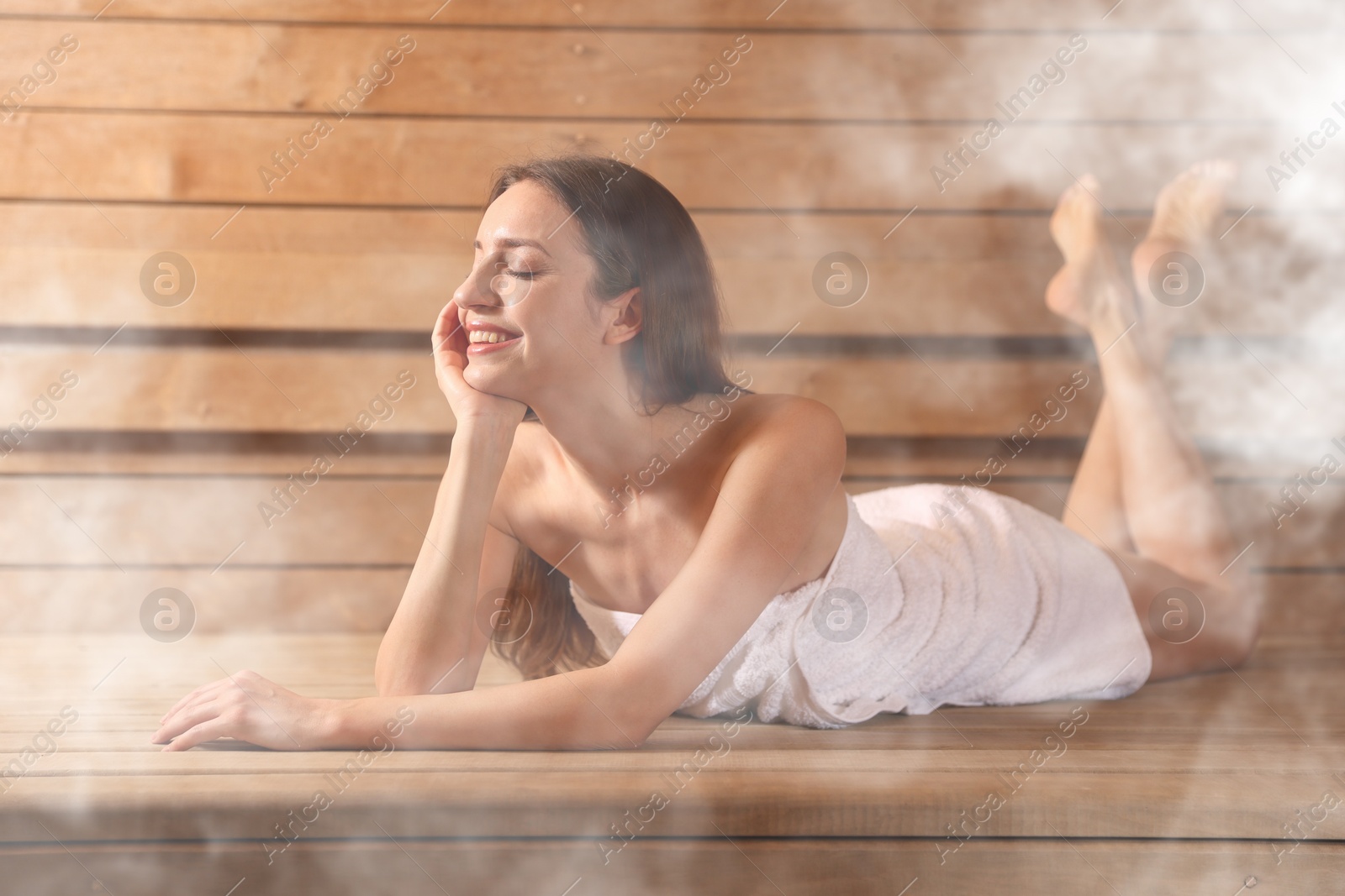 Beautiful woman relaxing on wooden bench surrounded by steam in sauna Image of Beautiful woman relaxing on wooden bench surrounded by steam in sauna
