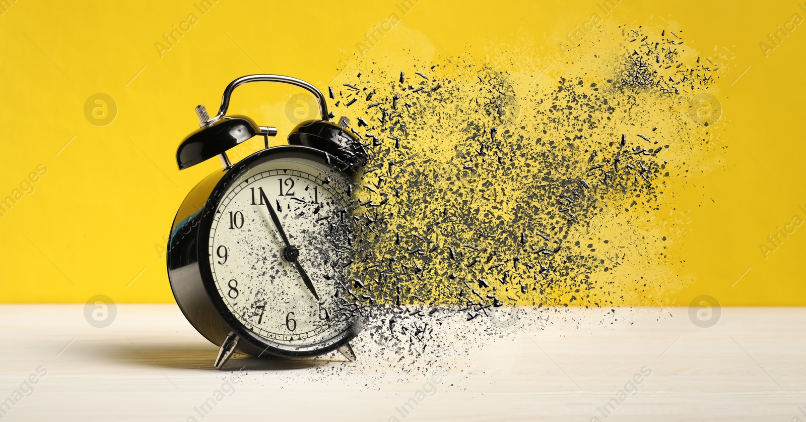 Alarm clock dissolving on white wooden table against yellow background, banner. Time is running out Image of Alarm clock dissolving on white wooden table against yellow background, banner. Time is running out