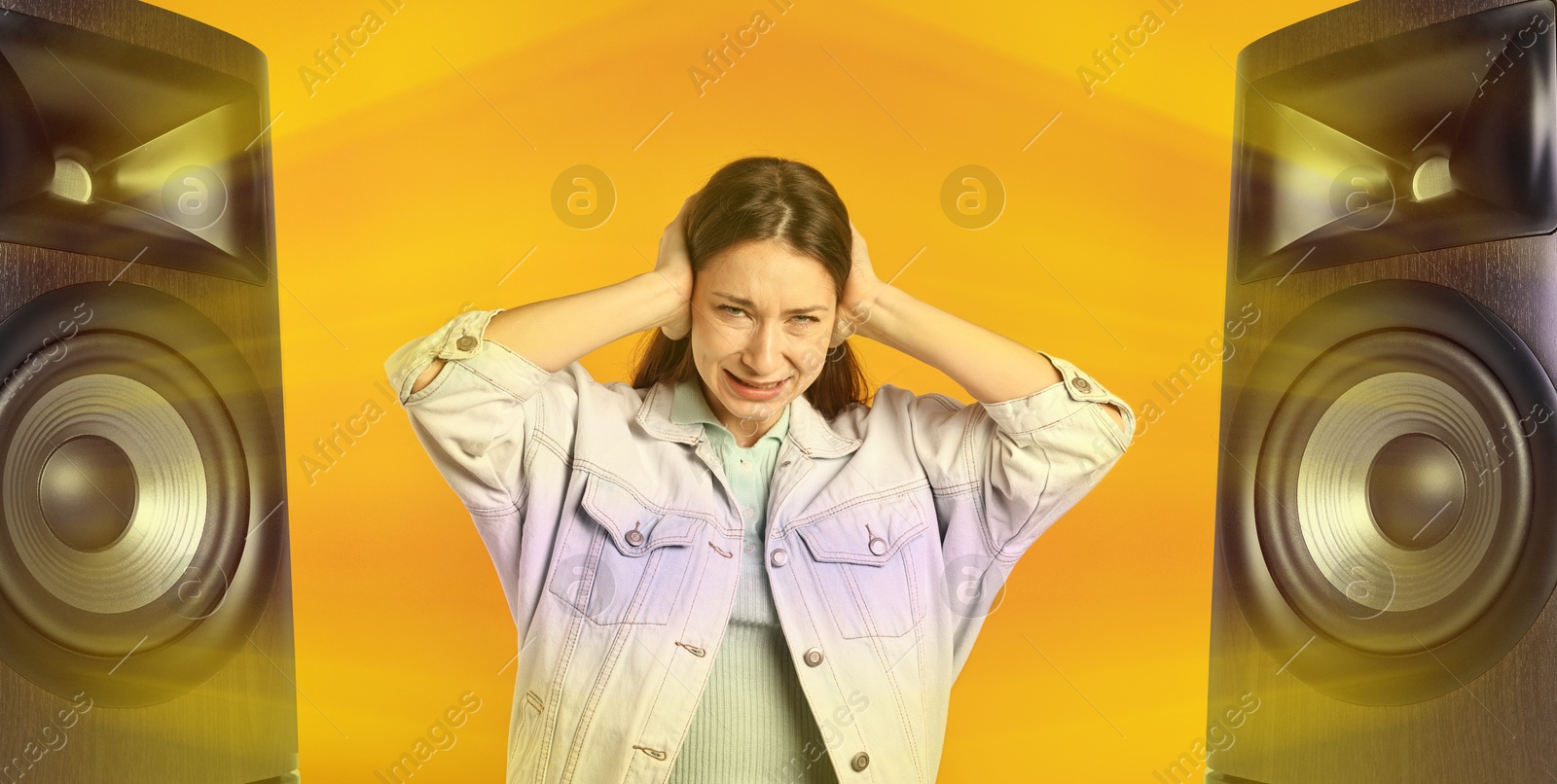 Annoyed woman covering her ears from loud sound of audio speakers on orange background Image of Annoyed woman covering her ears from loud sound of audio speakers on orange background