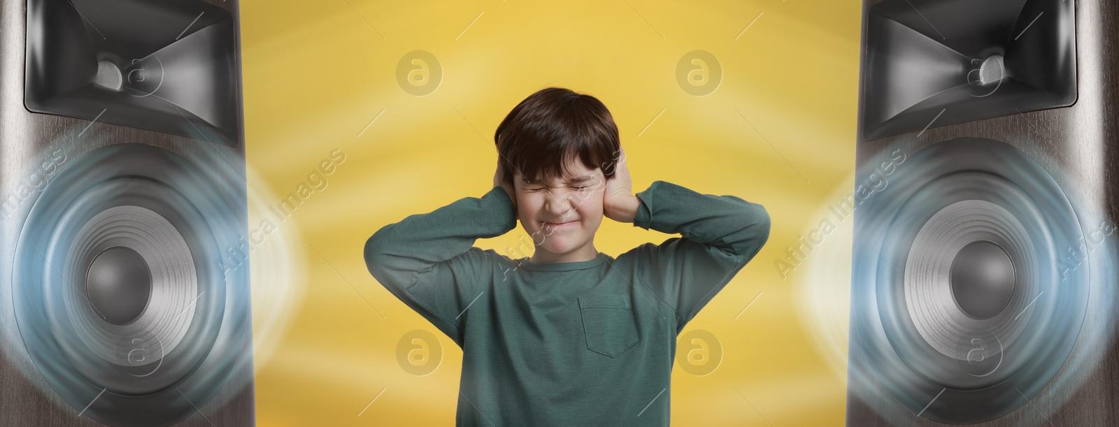 Annoyed boy covering his ears from loud sound of audio speakers on yellow background Image of Annoyed boy covering his ears from loud sound of audio speakers on yellow background