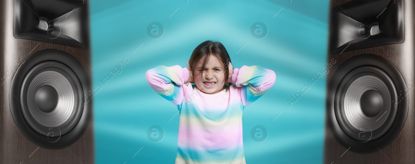 Annoyed girl covering her ears from loud sound of audio speakers on light blue background Image of Annoyed girl covering her ears from loud sound of audio speakers on light blue background