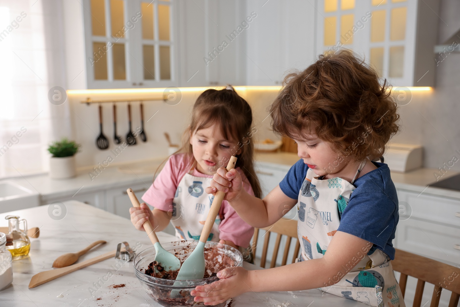 Cooking recipe. Cute children mixing dough for cookies at table in kitchen Photo of Cooking recipe. Cute children mixing dough for cookies at table in kitchen