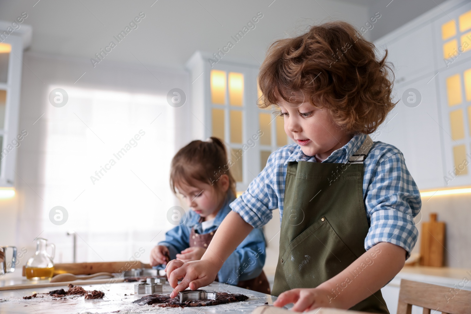 Cooking recipe. Little children cutting cookie dough with cutters at table indoors. Space for text Photo of Cooking recipe. Little children cutting cookie dough with cutters at table indoors. Space for text