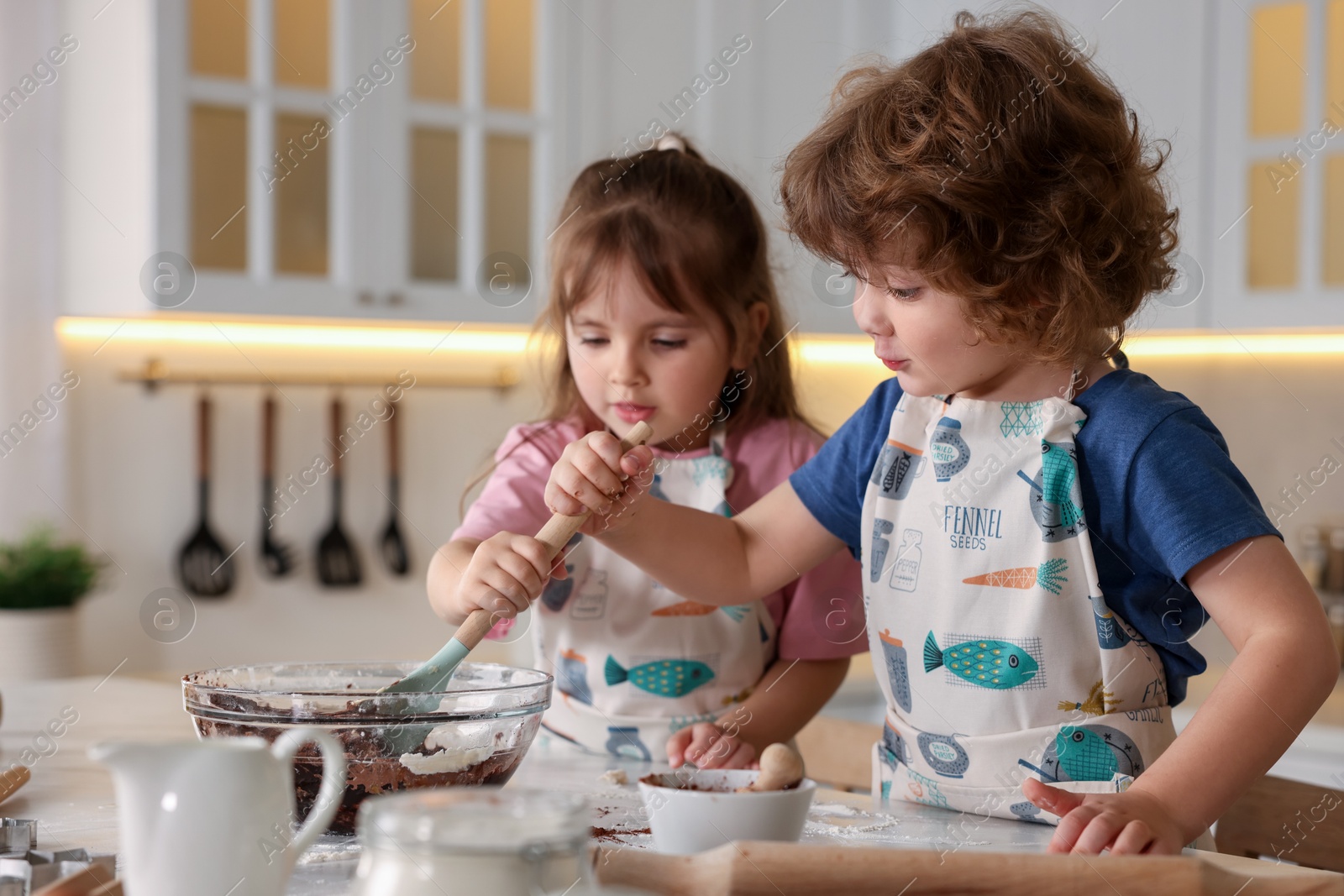 Cooking recipe. Cute children mixing dough for cookies at table in kitchen Photo of Cooking recipe. Cute children mixing dough for cookies at table in kitchen