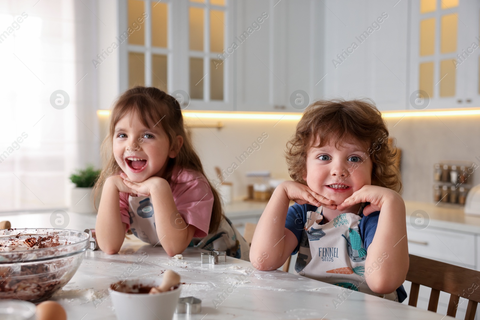 Little children having fun while cooking at table in kitchen Photo of Little children having fun while cooking at table in kitchen