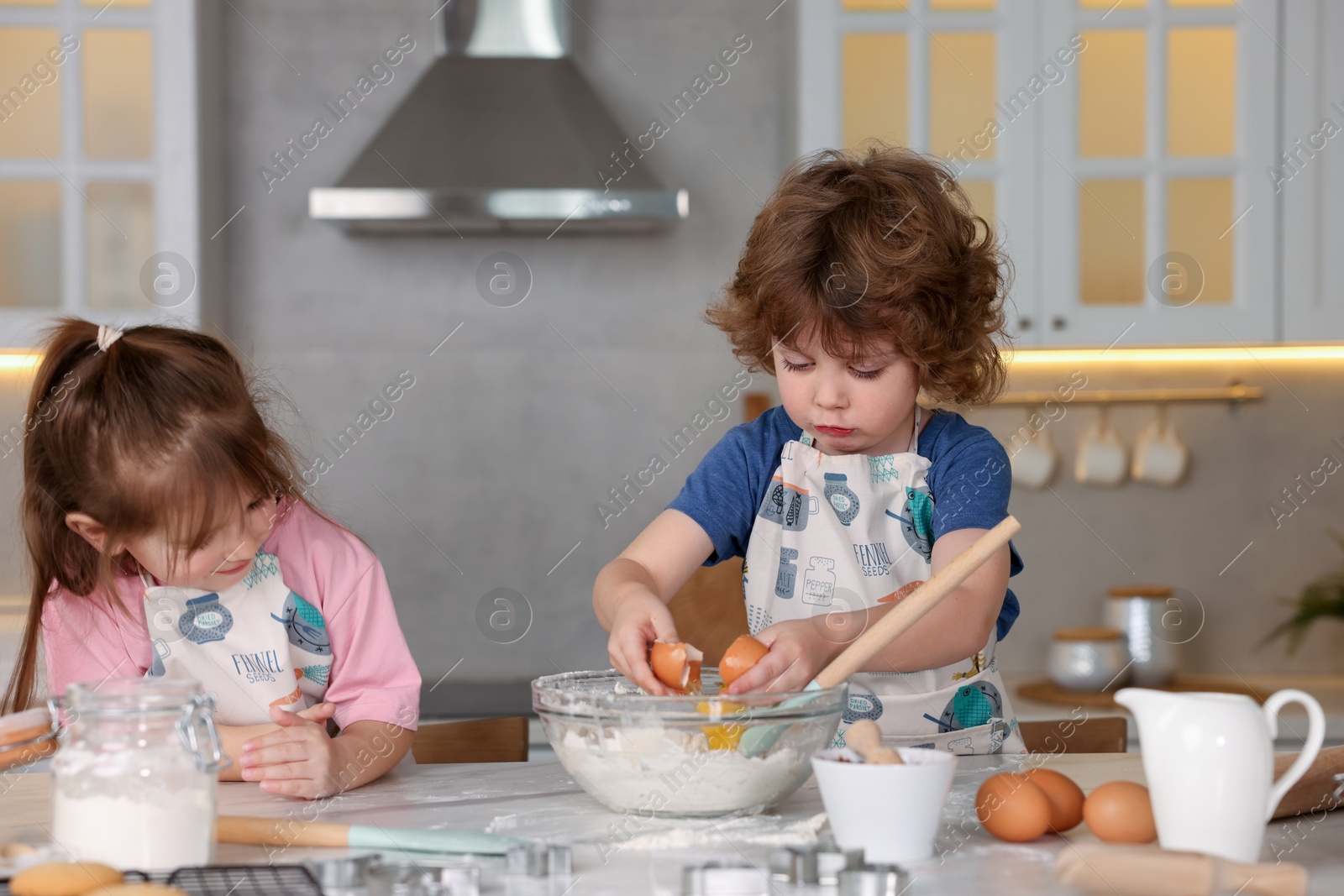 Cooking recipe. Cute children making dough for cookies at table in kitchen Photo of Cooking recipe. Cute children making dough for cookies at table in kitchen