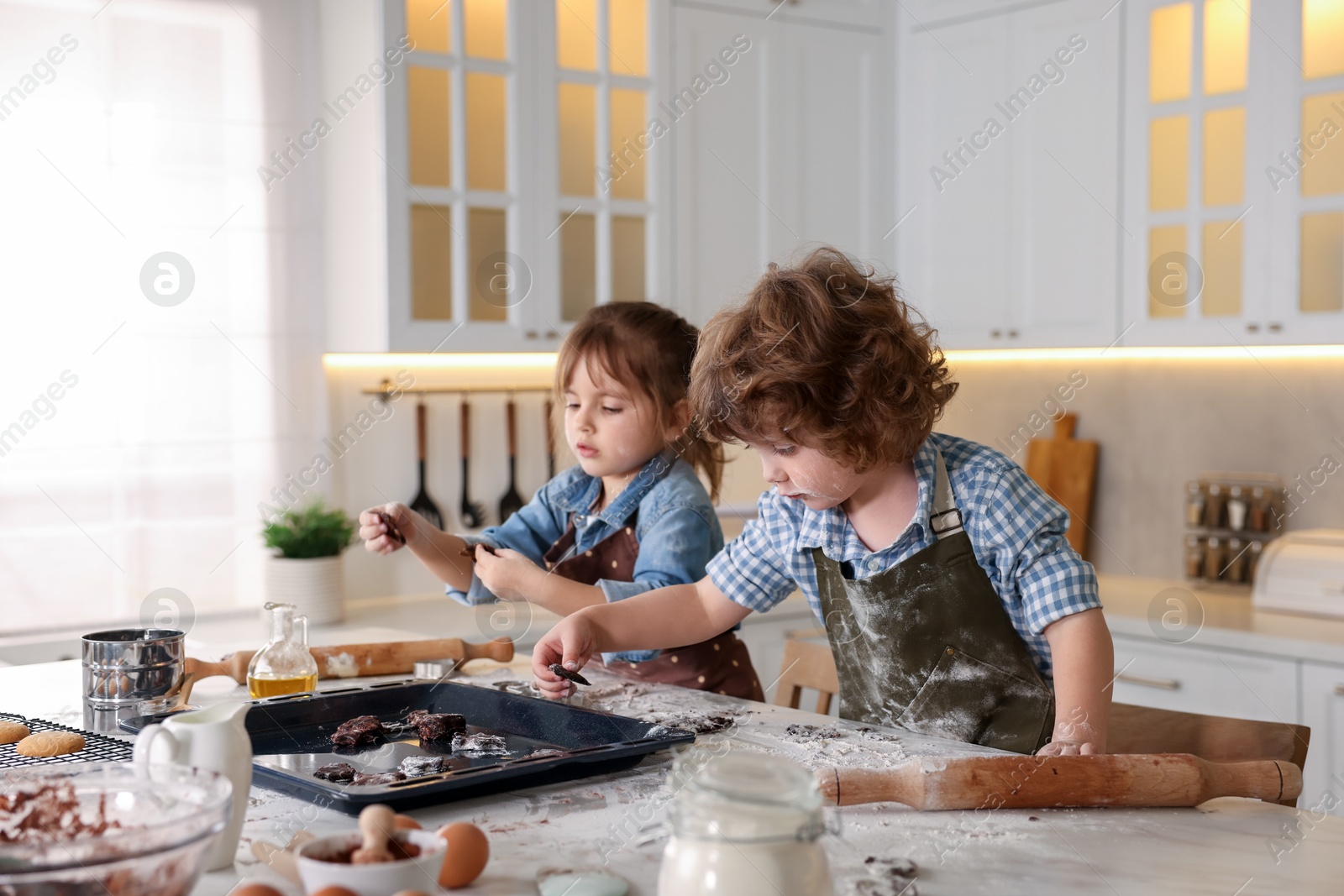 Cooking recipe. Children putting raw cookies onto baking dish at table in kitchen Photo of Cooking recipe. Children putting raw cookies onto baking dish at table in kitchen