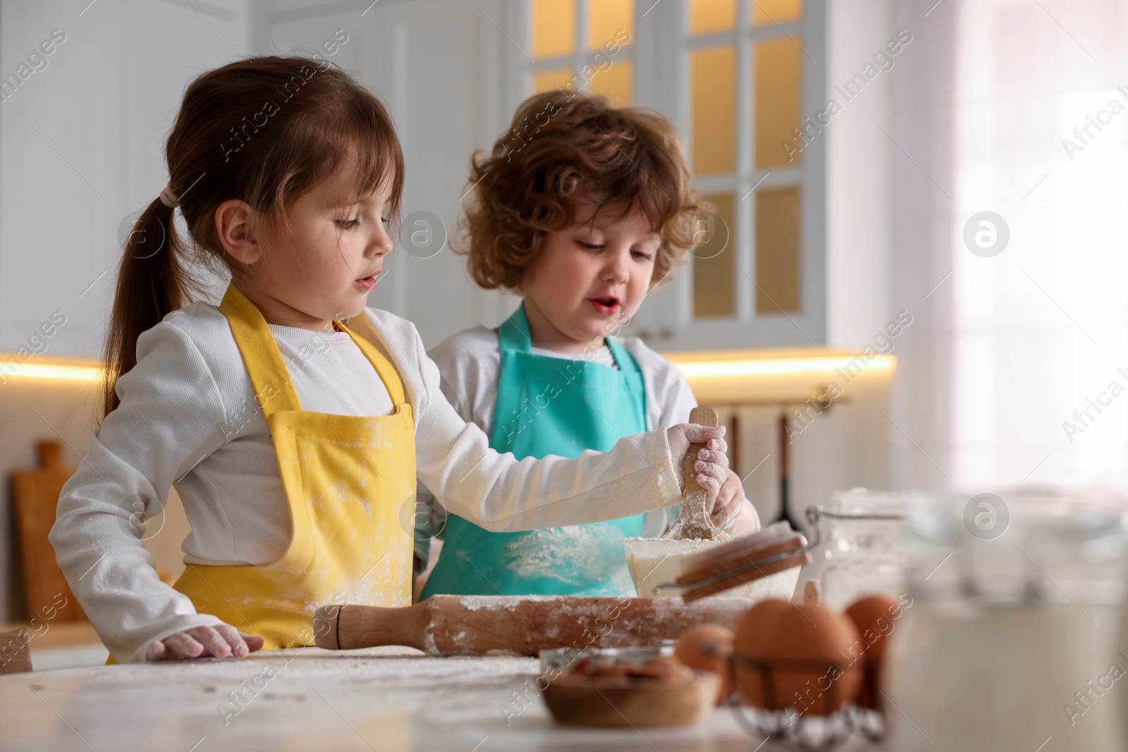 Cooking recipe. Little children making dough for cookies at table in kitchen Photo of Cooking recipe. Little children making dough for cookies at table in kitchen