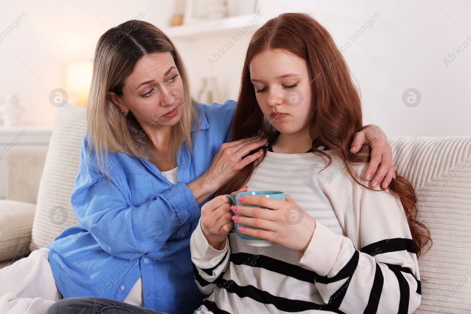 Mother consoling her upset daughter on sofa at home Photo of Mother consoling her upset daughter on sofa at home