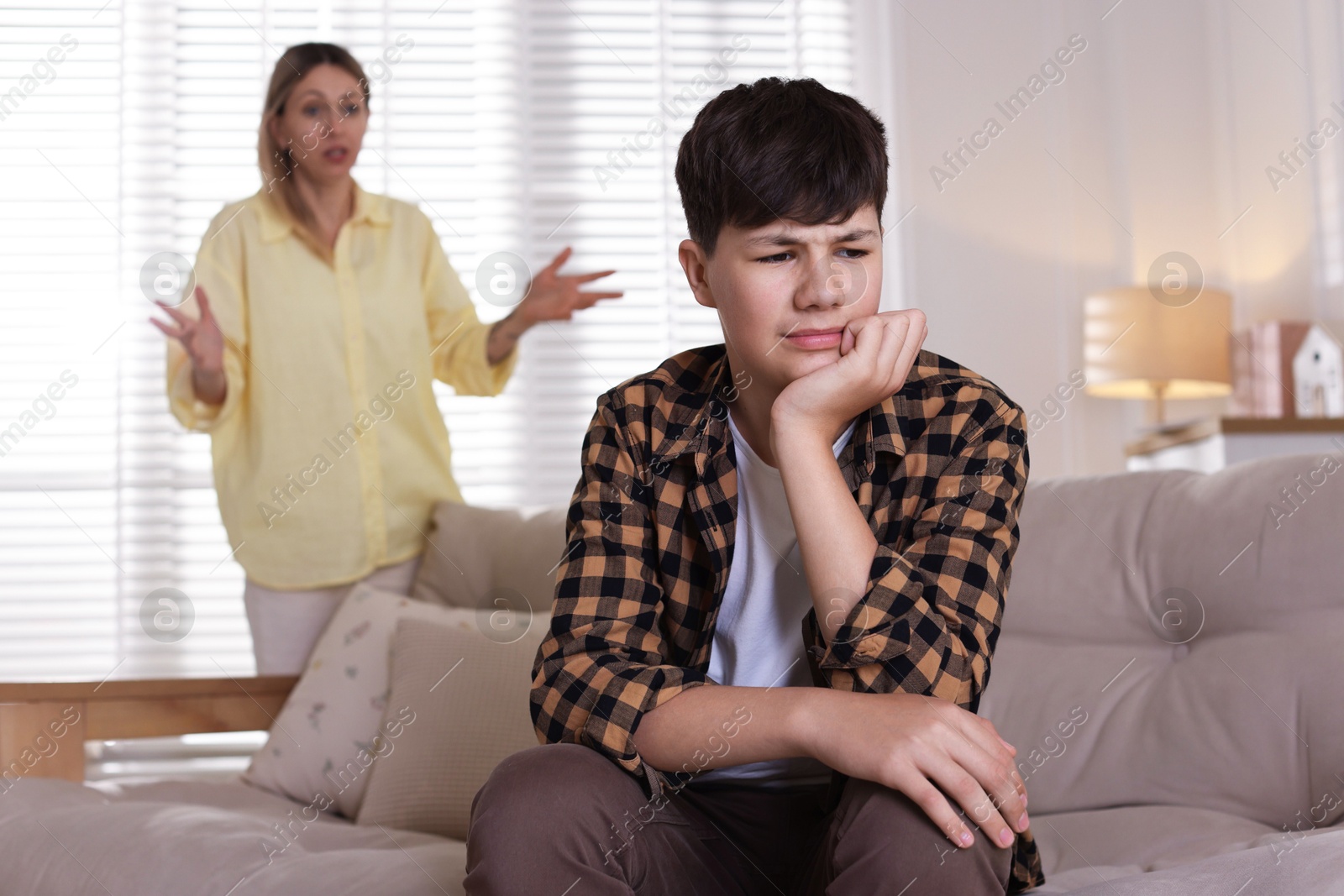 Mother scolding her teenage son at home, selective focus Photo of Mother scolding her teenage son at home, selective focus