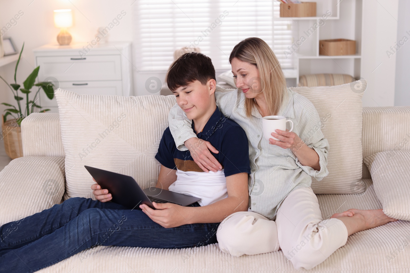 Mother and her son watching something on laptop at home Photo of Mother and her son watching something on laptop at home