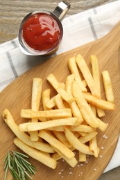 Photo of Tasty french fries with ketchup and rosemary on wooden table, top view