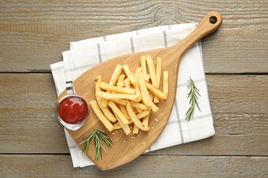 Photo of Tasty french fries with ketchup and rosemary on wooden table, top view
