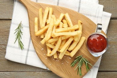 Photo of Tasty french fries with ketchup and rosemary on wooden table, top view