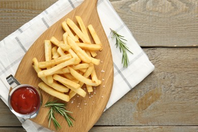 Photo of Tasty french fries with ketchup and rosemary on wooden table, top view