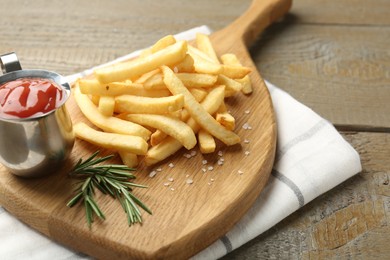 Photo of Tasty french fries with ketchup and rosemary on wooden table, closeup
