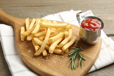 Photo of Tasty french fries with ketchup and rosemary on wooden table, closeup