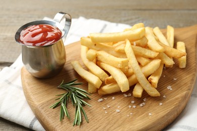 Photo of Tasty french fries with ketchup and rosemary on wooden table, closeup