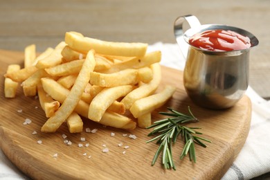 Photo of Tasty french fries with ketchup and rosemary on wooden table, closeup
