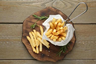 Photo of Tasty french fries with rosemary on wooden table, top view