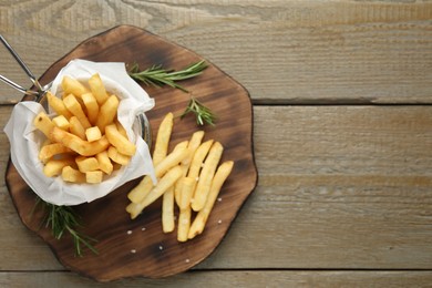 Photo of Tasty french fries with rosemary on wooden table, top view. Space for text