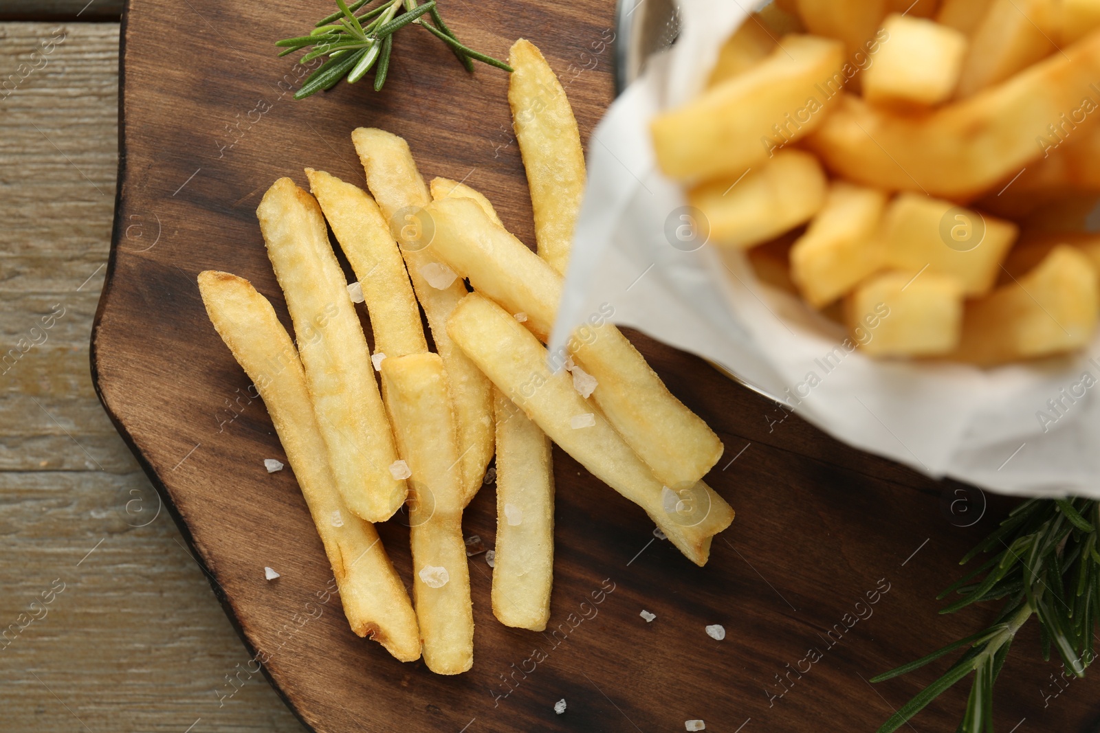 Photo of Tasty french fries with rosemary on wooden table, top view