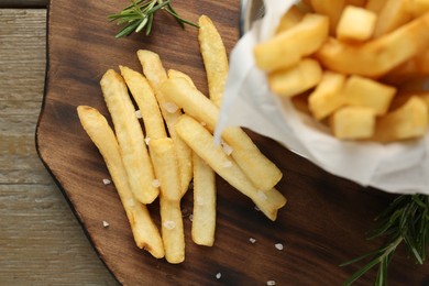 Photo of Tasty french fries with rosemary on wooden table, top view