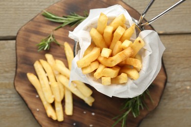 Photo of Tasty french fries with rosemary on wooden table, top view
